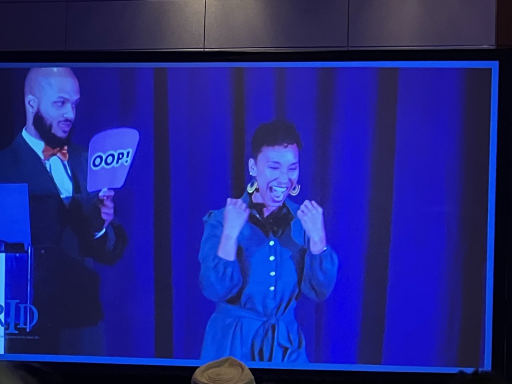 Tiffany and Paris are pictured in a video -- Tiffany is signing while Paris is looking on, holding a sign that says "OOP!"